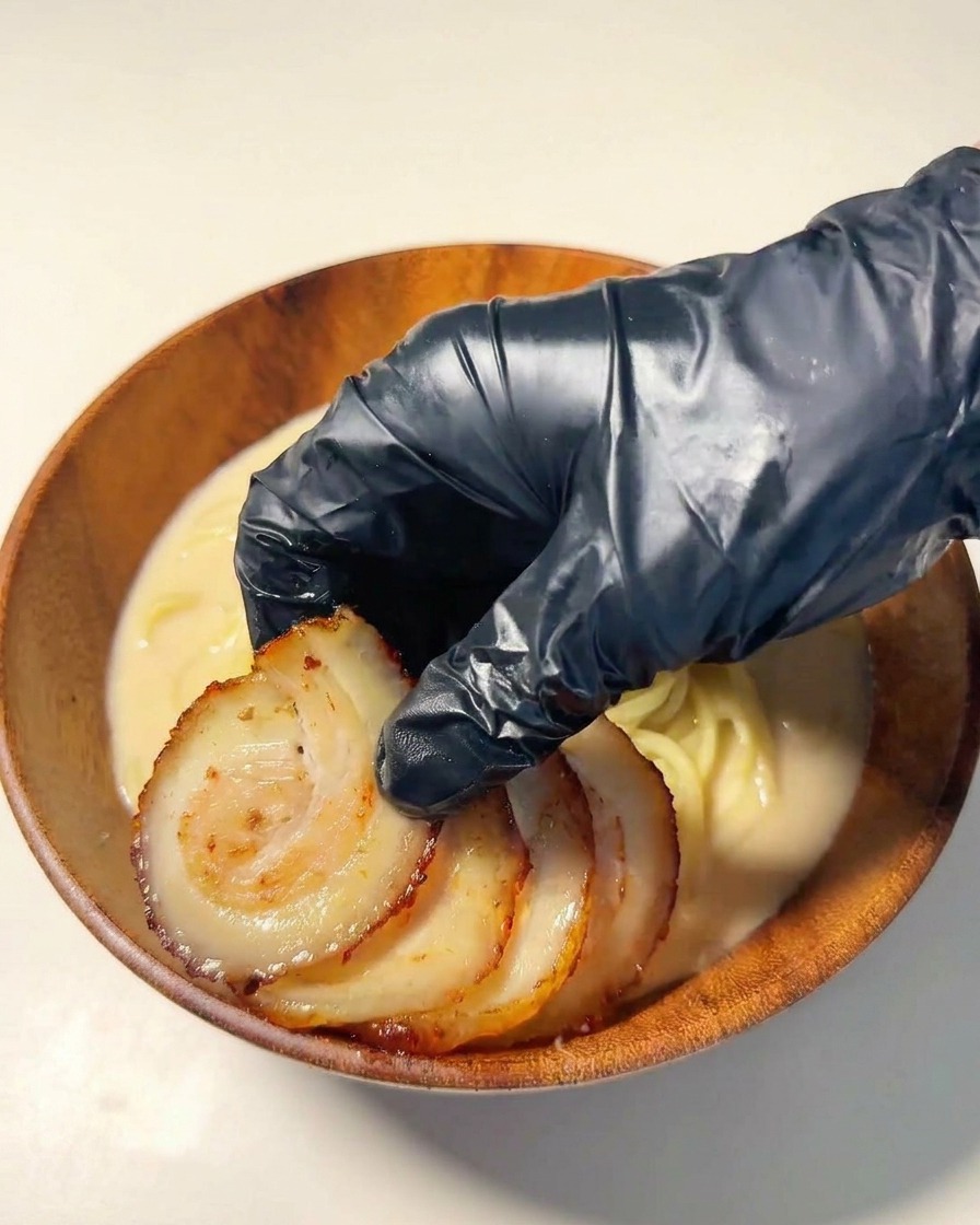 麺の上にチャーシューの輪切りを並べている様子。