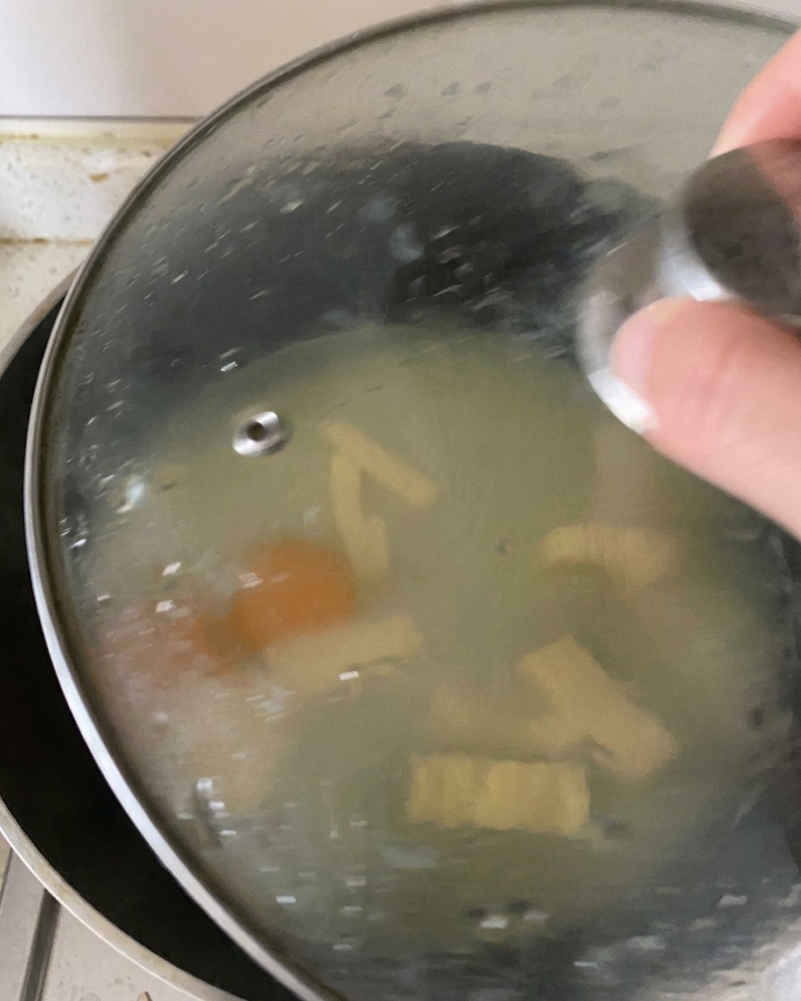 フライパンにガラスの蓋がされ、中に蒸気を閉じ込めて卵に火を通し、チーズを溶かしている状態。