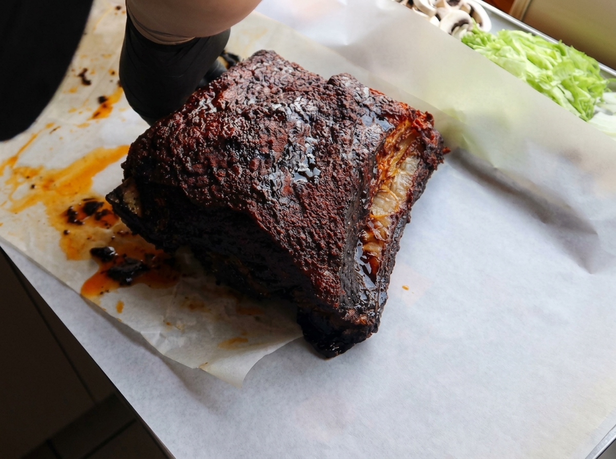 4時間焼いて色が濃くなったスペアリブを、白いクッキングシートの上に置いている様子。