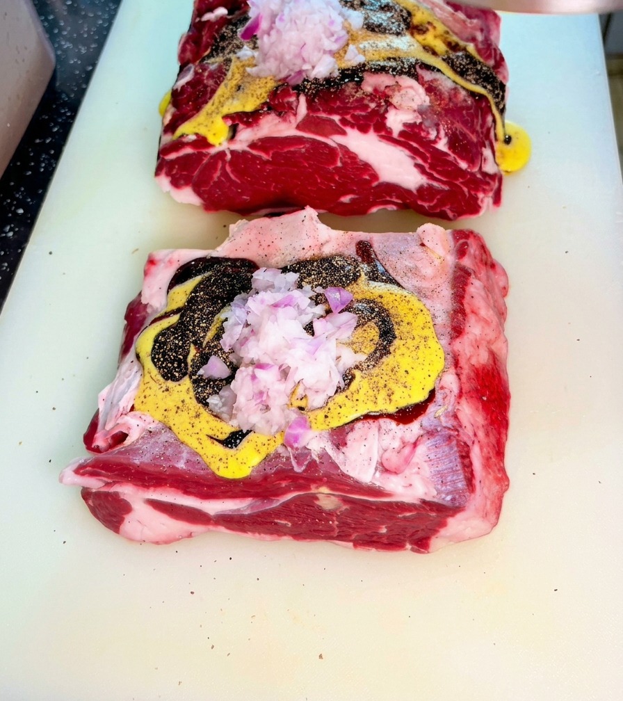 まな板の上で、各種ソースと刻んだ赤玉ねぎがのった生の牛肉。