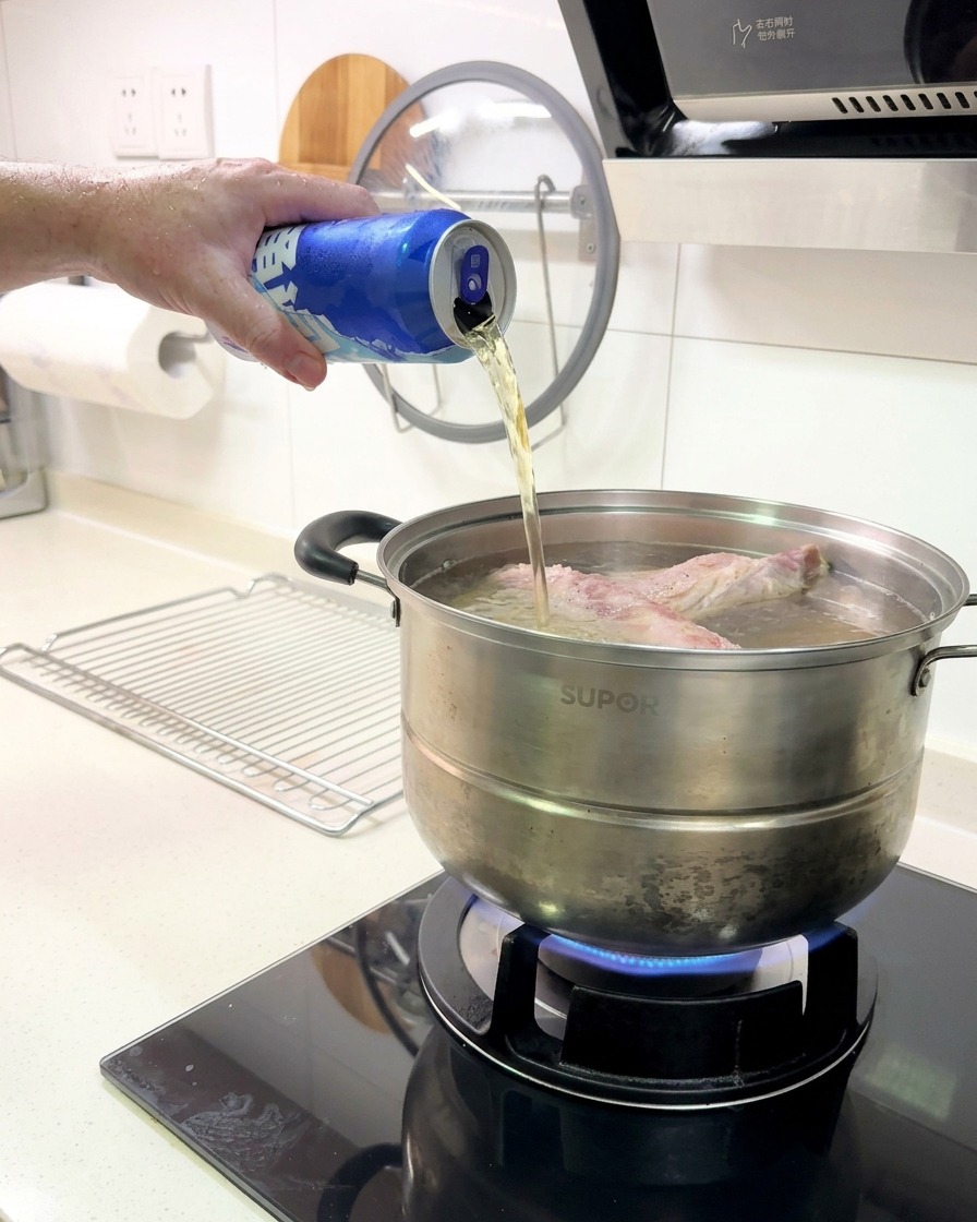 茹でているリブの鍋に、缶ビールを注ぎ入れている様子。