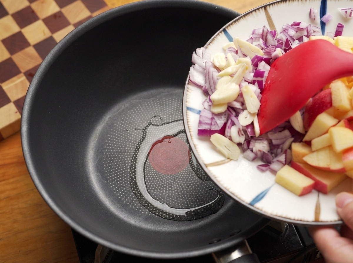 熱したフライパンに赤玉ねぎとにんにくを入れている様子。