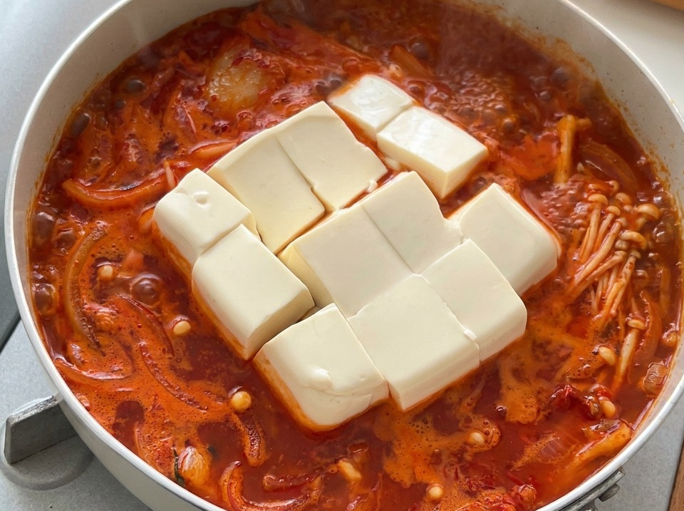 グツグツと煮立つ熱いキムチチゲの中に、大きめに切った白い絹ごし豆腐が入っている様子。