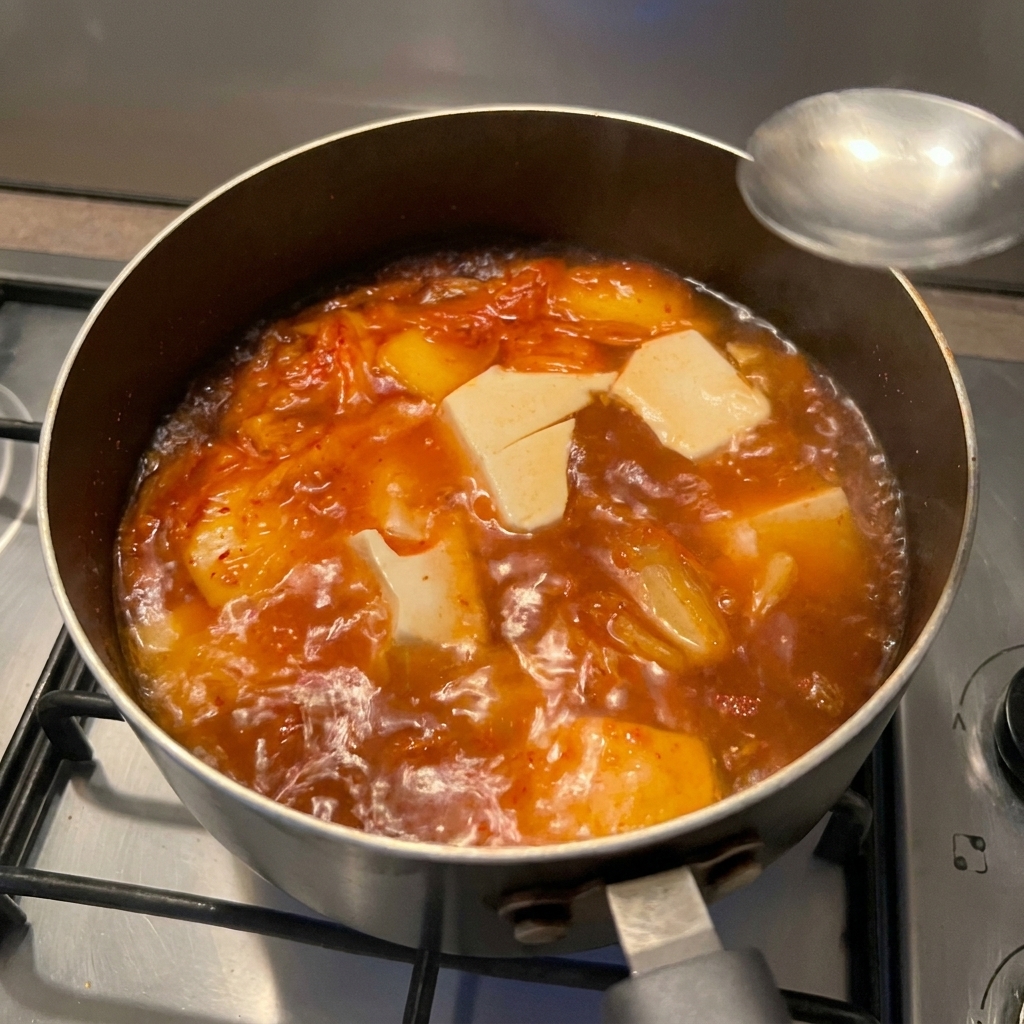 simmering 状態のスープに醤油を回し入れている様子