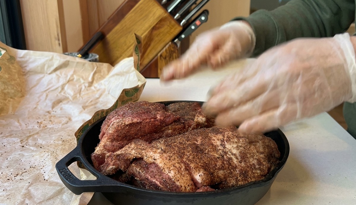 味付けされた豚肩ロースが鋳物スキレットに置かれ、予熱されたオーブンで焼く準備が整った状態。