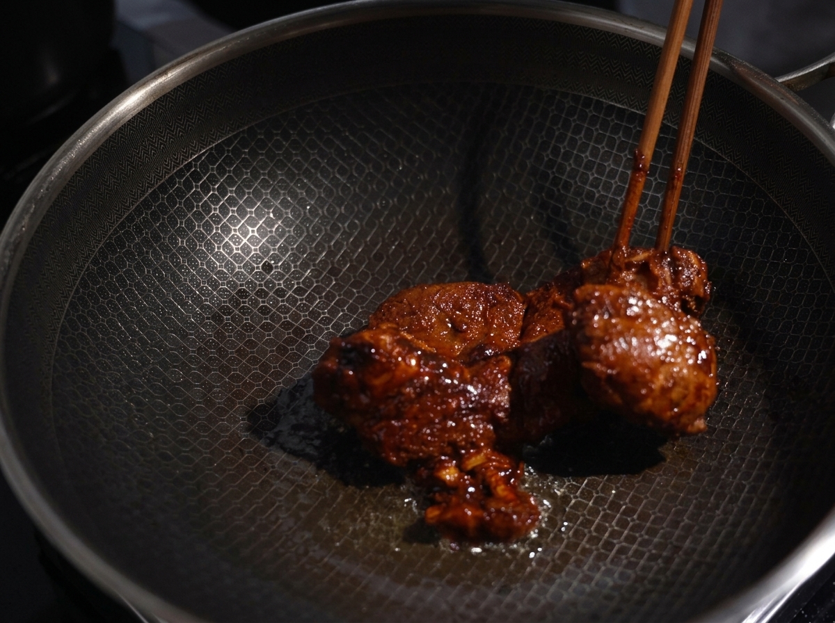 熱したフライパンで、スパイスを塗った豚肉を菜箸で裏返しながら焼いている様子。
