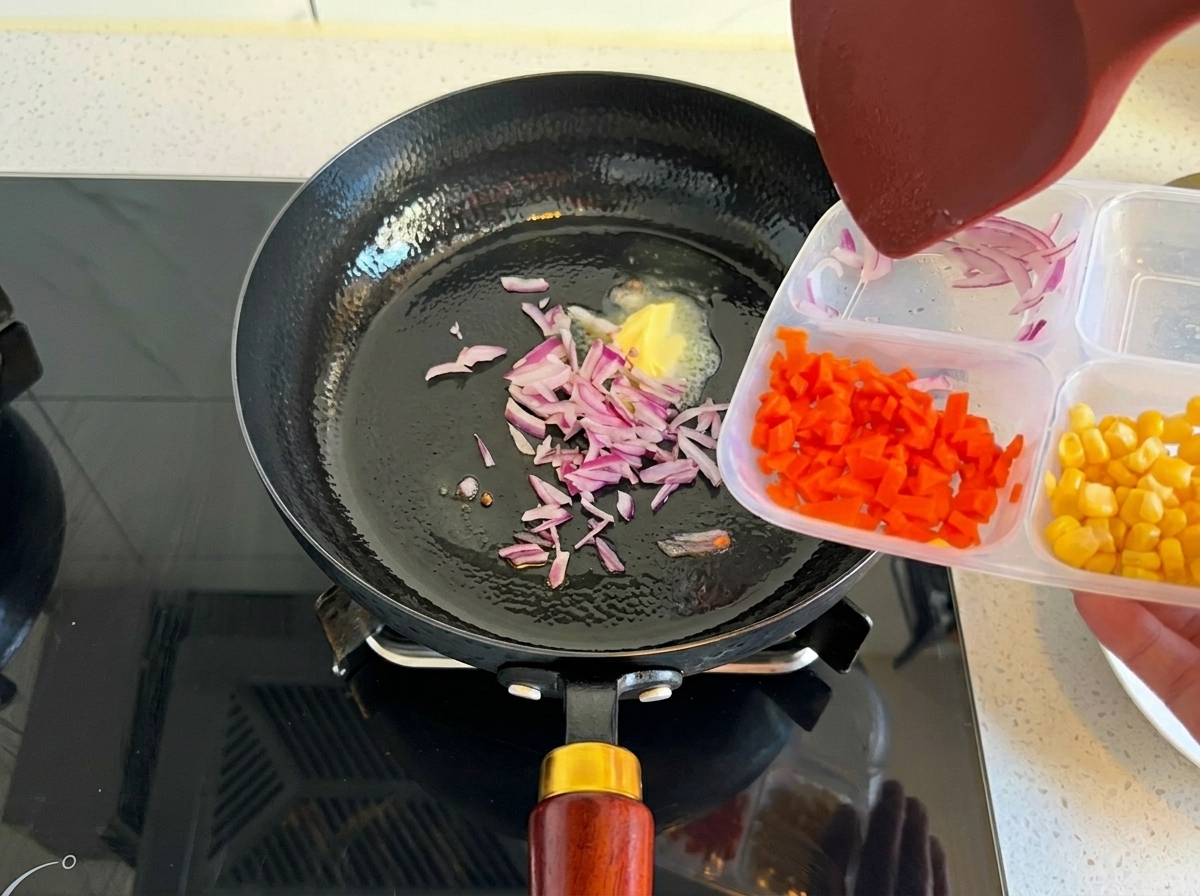 溶けたバターが入ったフライパンに、容器から赤玉ねぎを入れている様子。