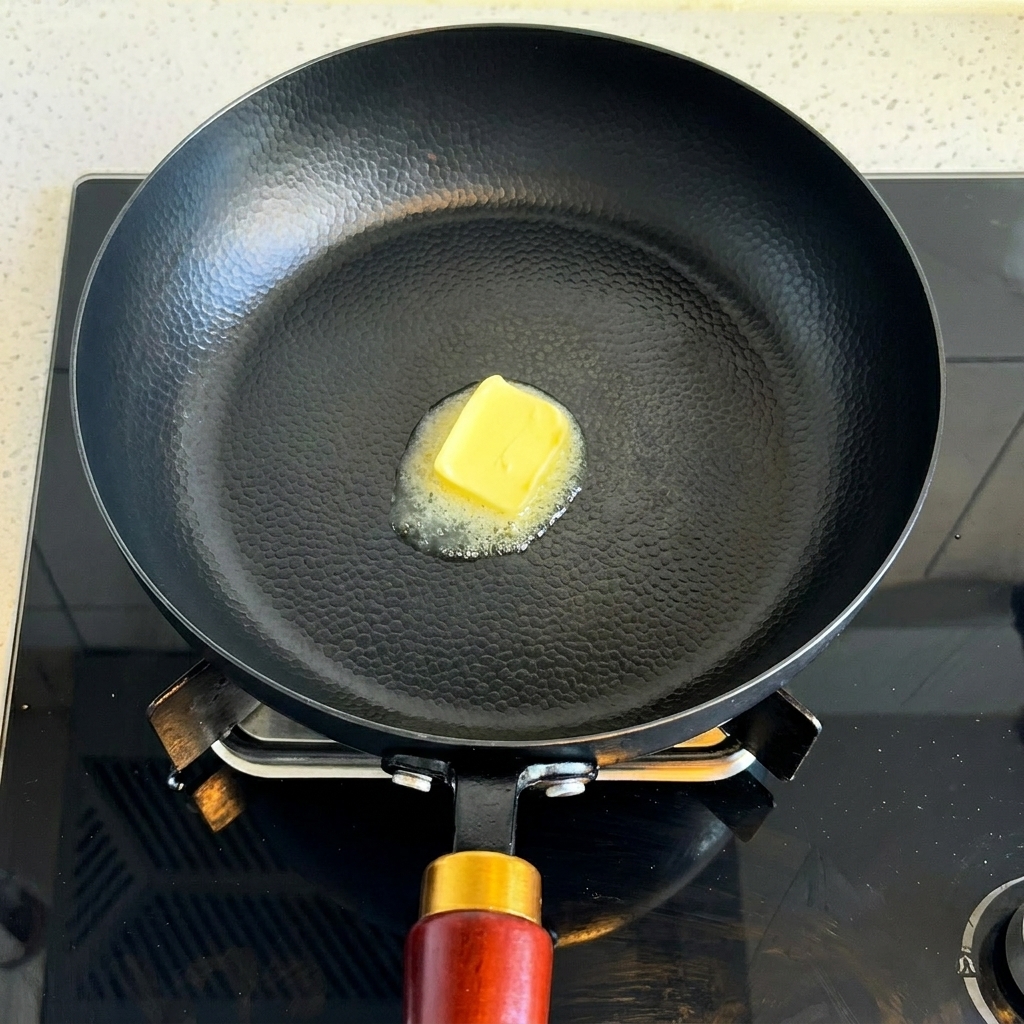 熱いフライパンの中で四角いバターが溶けている。