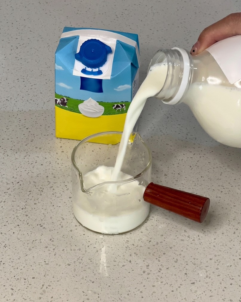生クリームが入ったガラスのピッチャーに、牛乳を注いで混ぜている様子
