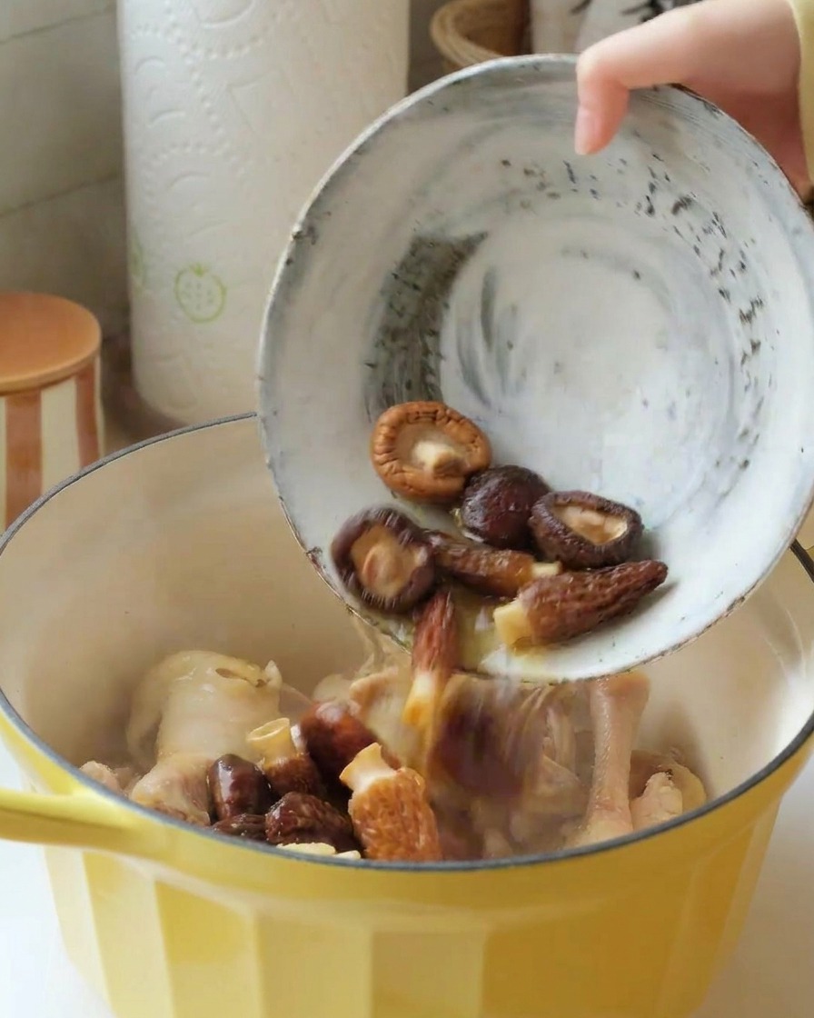 戻した椎茸とモリーユ茸を鶏肉の入った鍋に入れている様子。