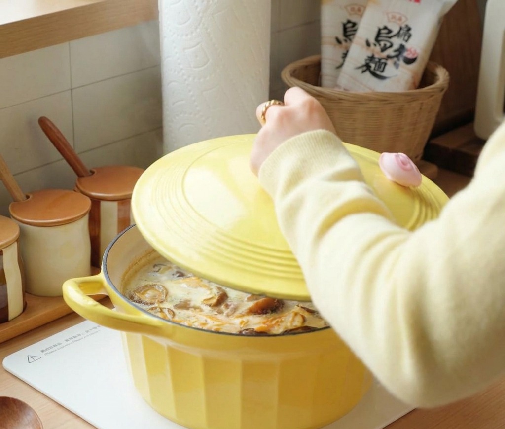 沸騰しているスープの鍋に黄色の蓋を閉めている様子。