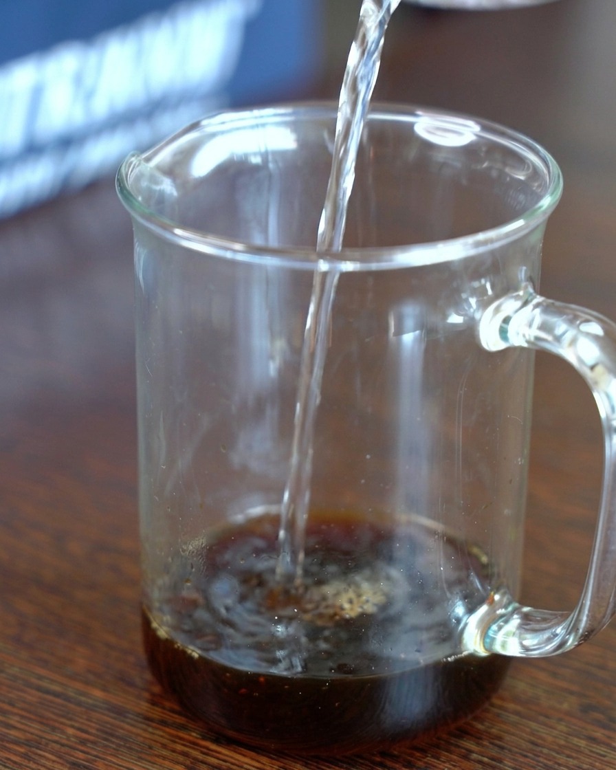 昆布醤油と砂糖が入った計量カップに、透明な水を注いでいる様子。