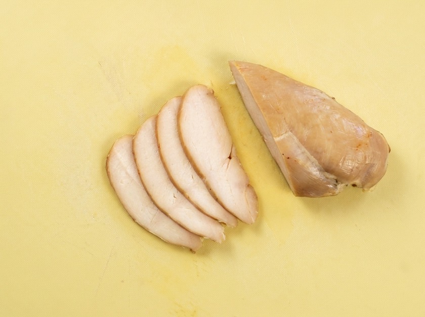 まな板の上で、均等な厚さにスライスされた鶏むね肉。