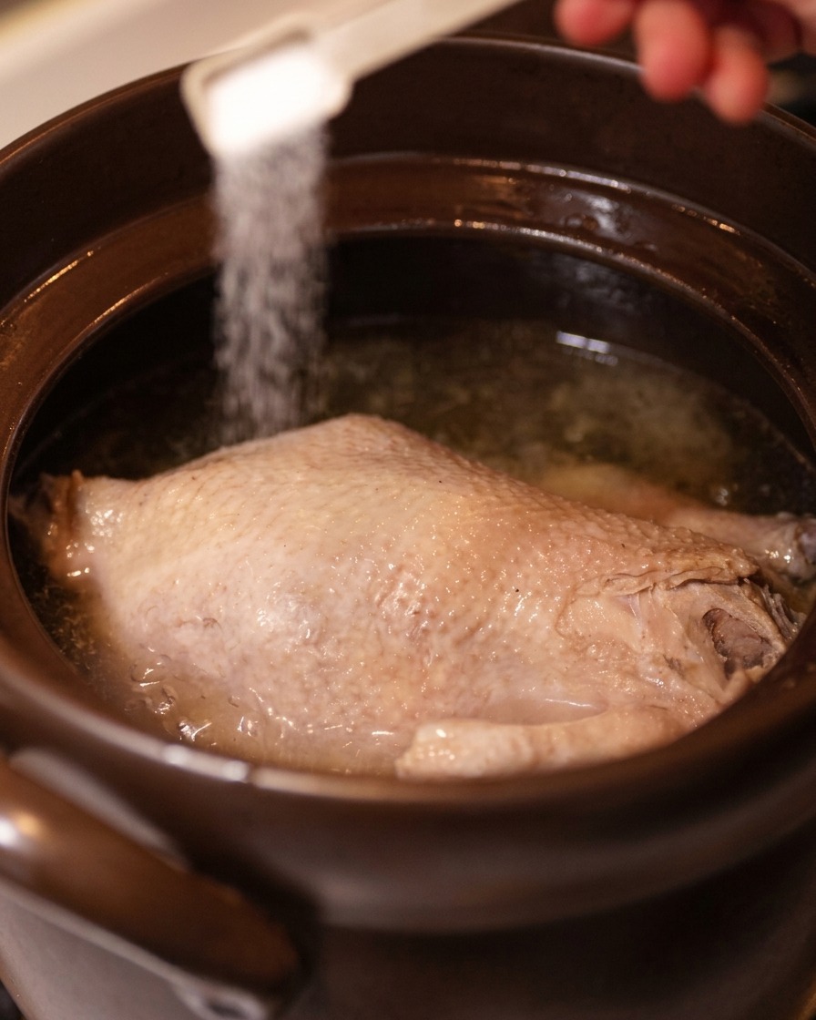 スープに塩を振り入れて味を調整している様子。
