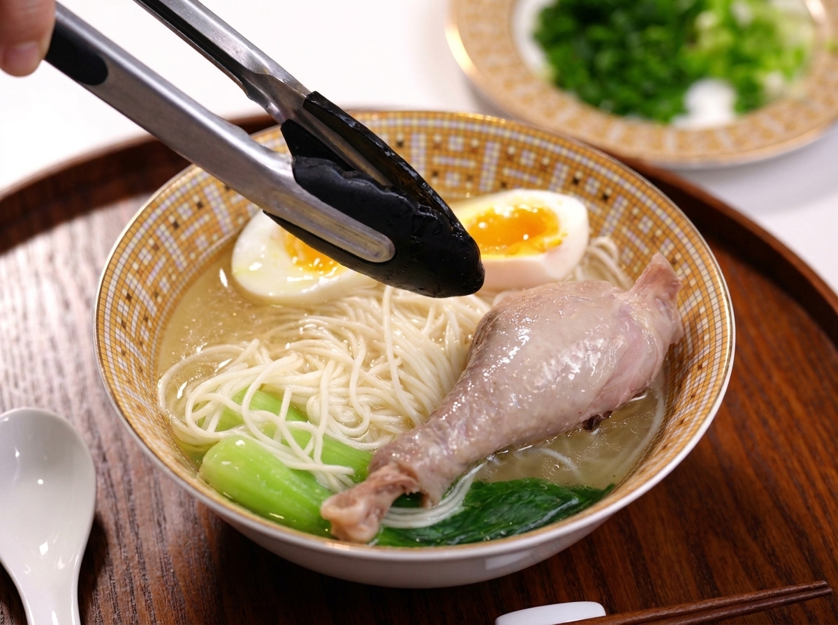 麺の上にスープで煮込んだ鶏もも肉をトッピングしている様子。