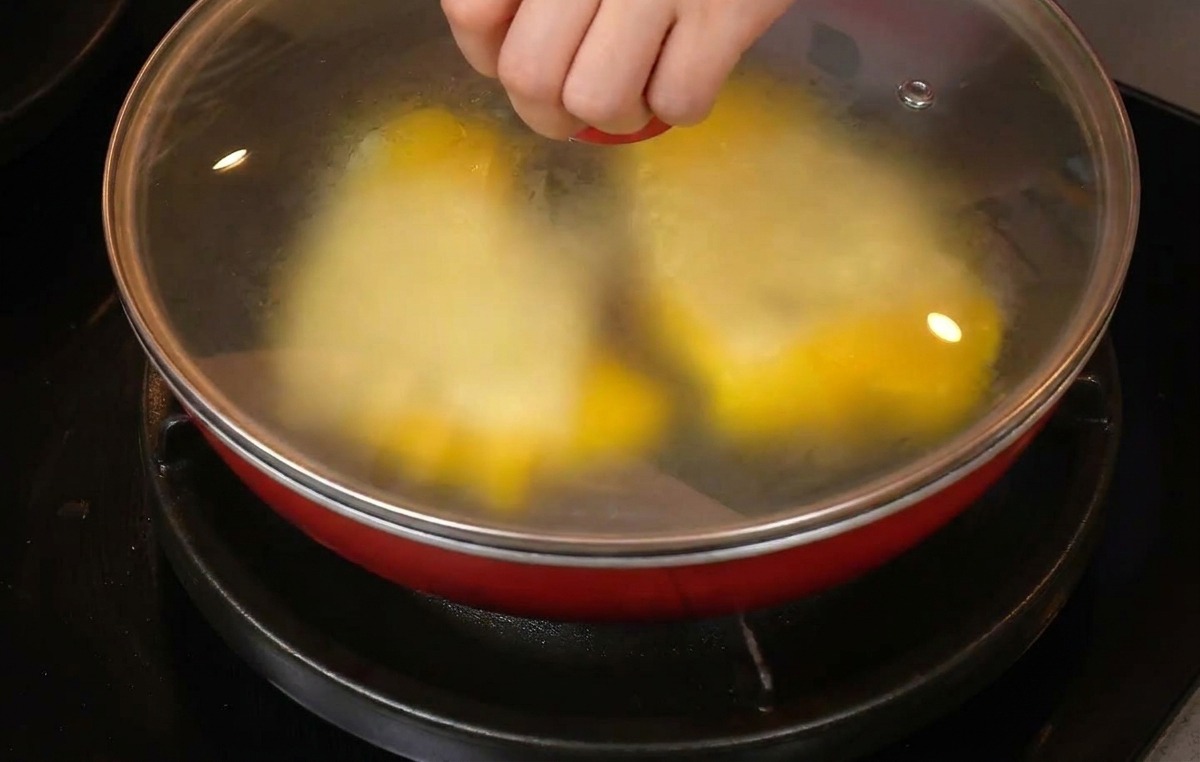 フライパンにガラス蓋をして、中のチーズが溶けるのを待っている様子。