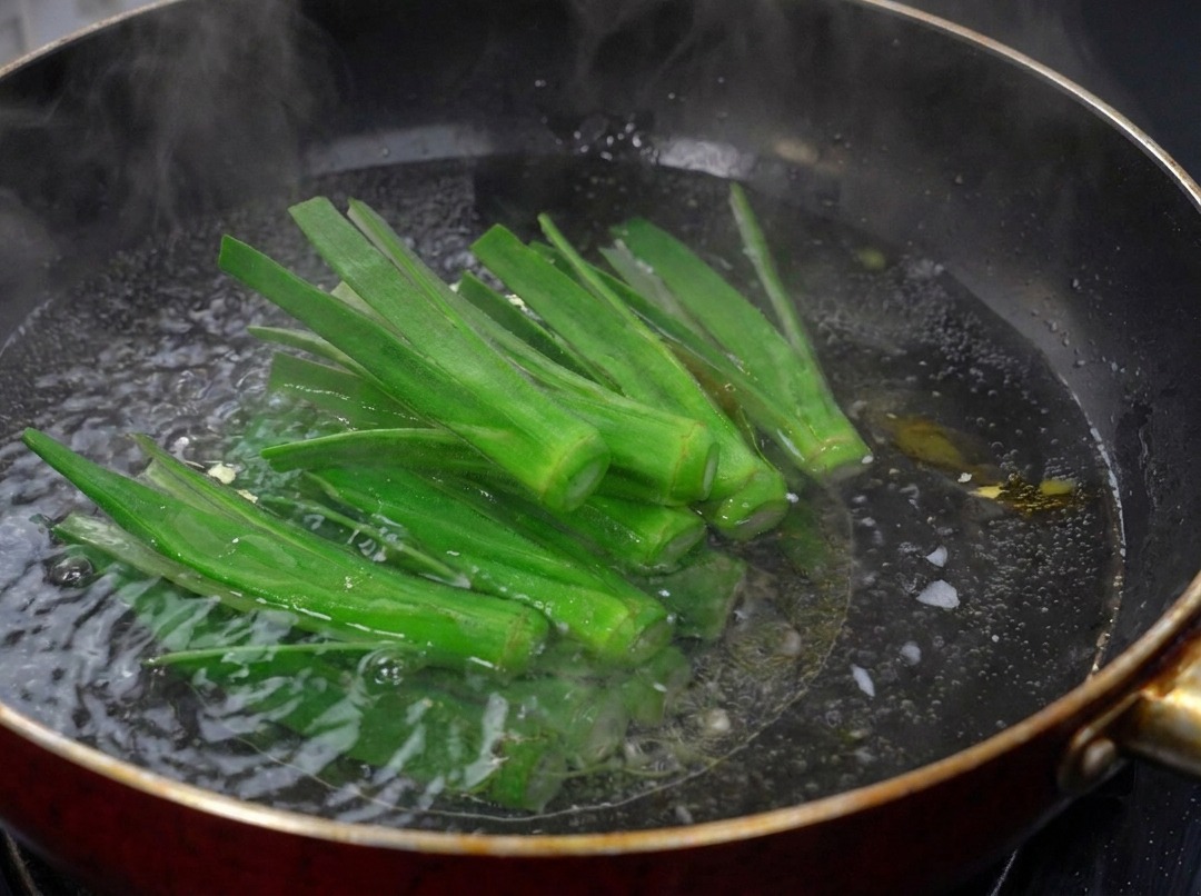 沸騰したお湯が入った中華鍋の中で、細かく割いたオクラをさっと茹でている様子。