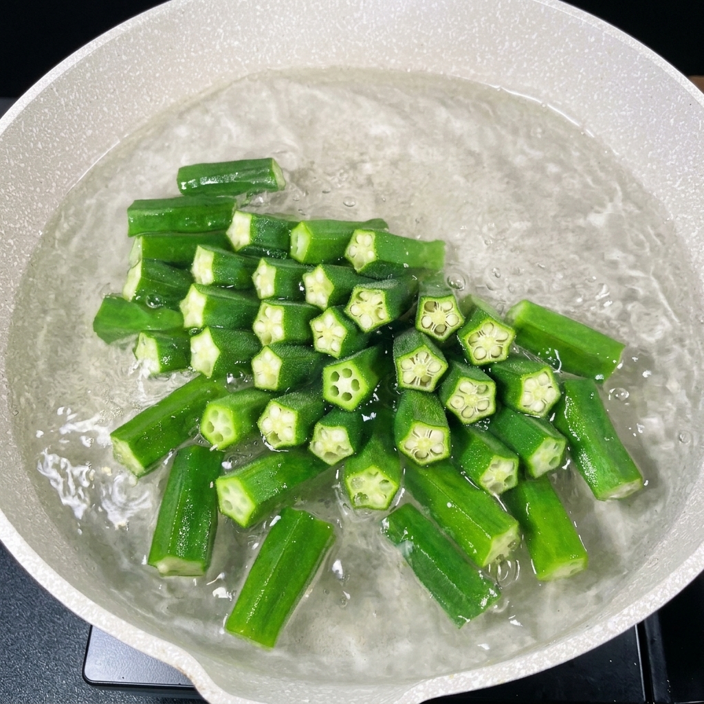 鮮やかな緑色になったカットオクラが鍋の中で茹でられている様子。