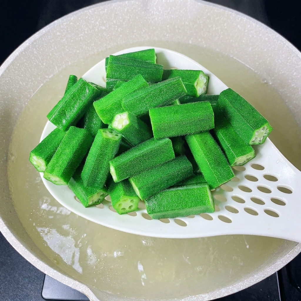 白いお玉で生姜のスライスとネギを沸騰したお湯に入れている様子。