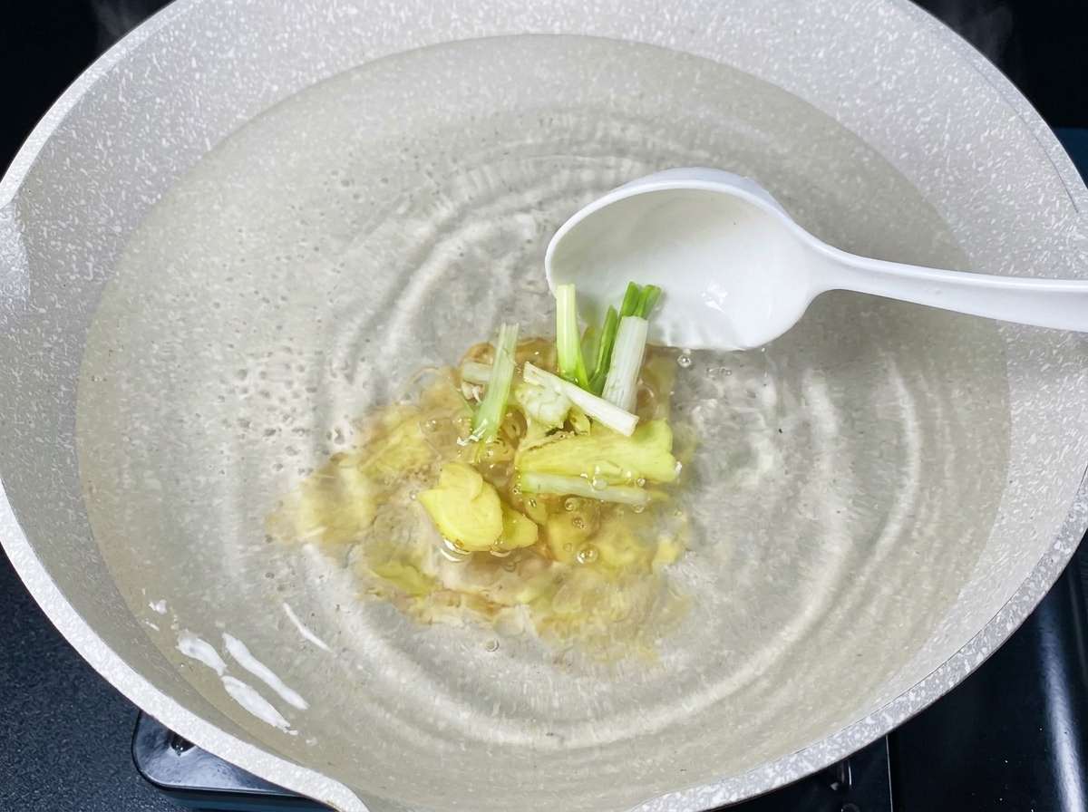 生姜とネギが入ったお湯に生のあさりを投入している様子。