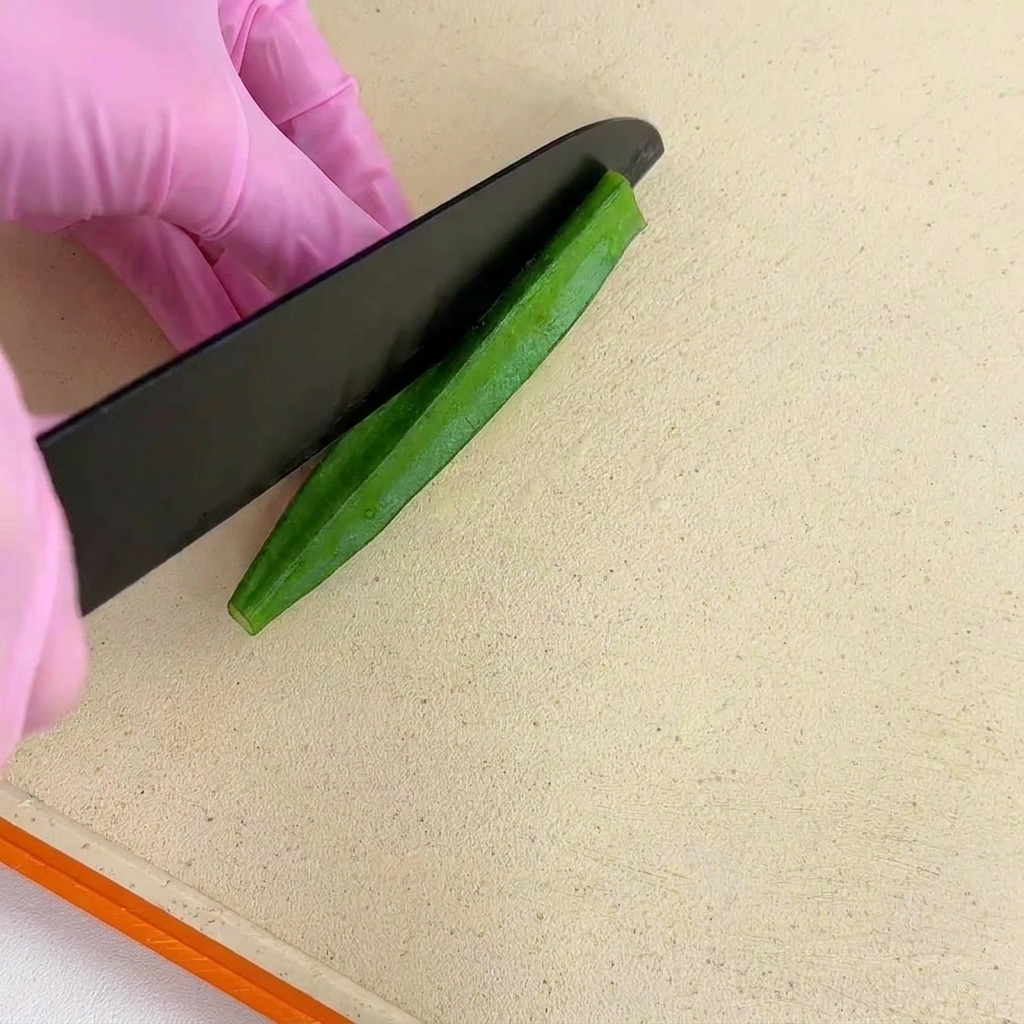 オクラを縦方向にまっすぐ半分に切る様子。