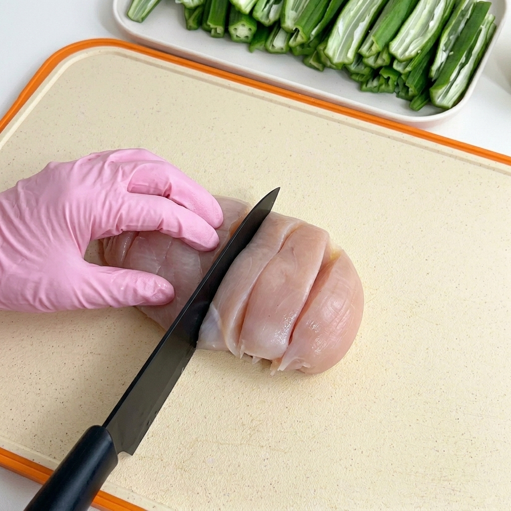 まな板の上で鶏むね肉をぶつ切りにする様子。