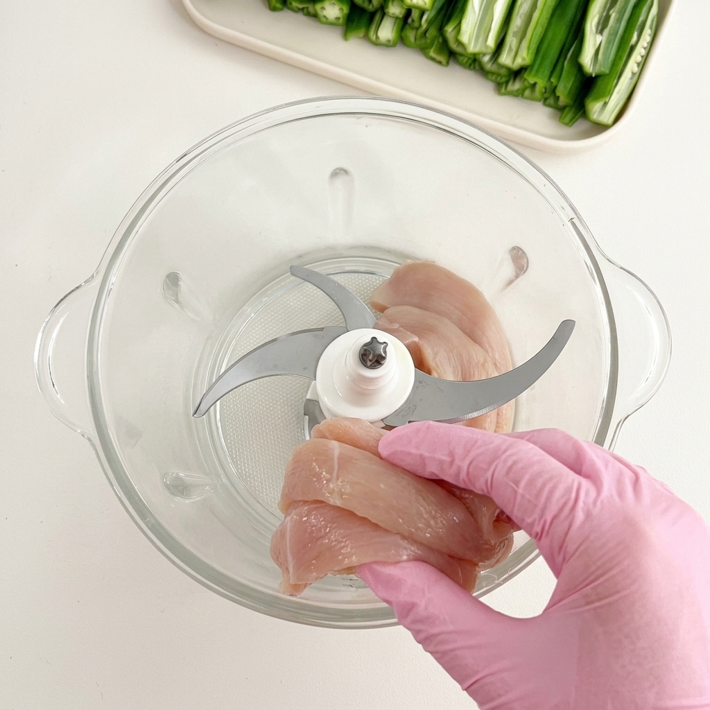 フードプロセッサーの容器に鶏肉を投入する様子。