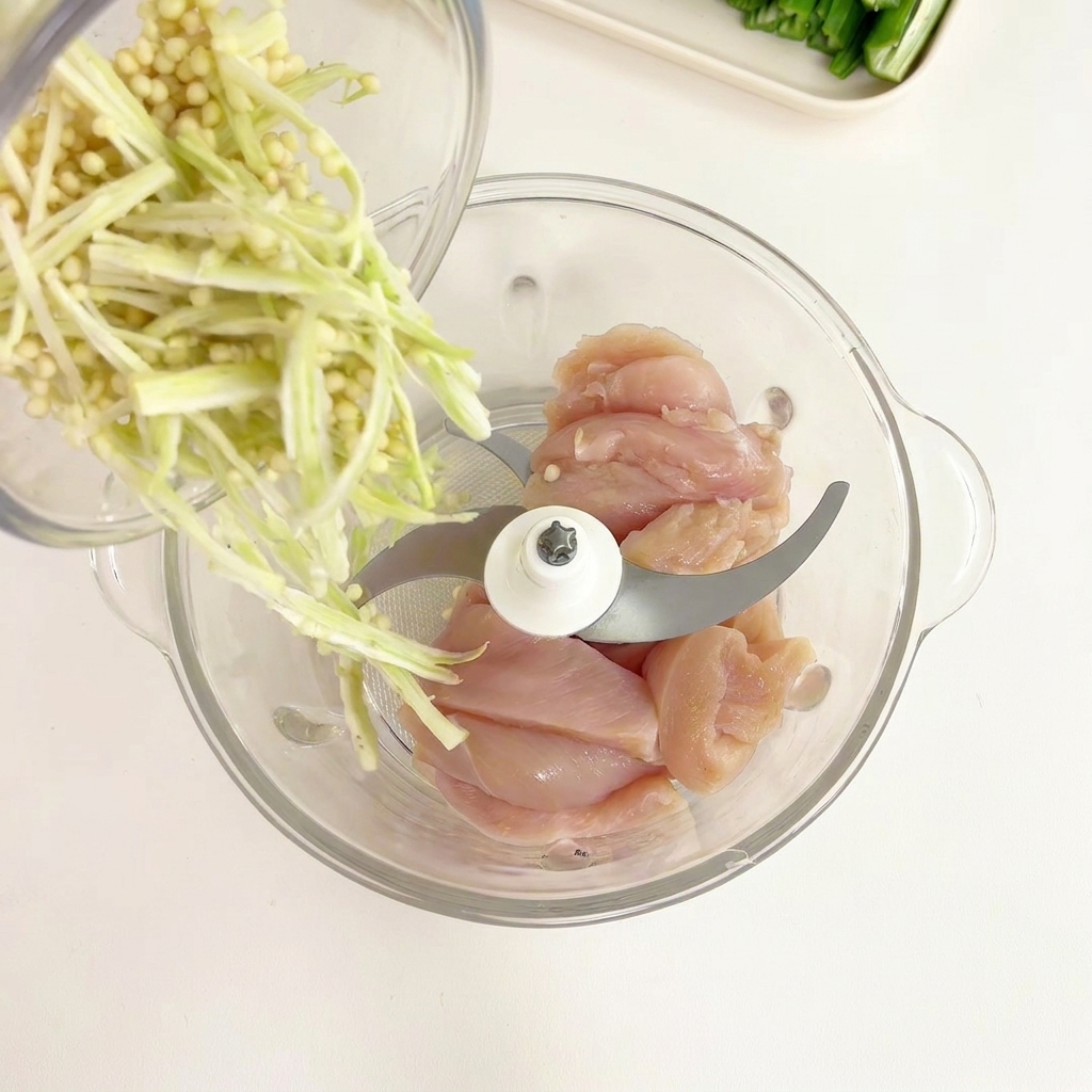 鶏肉が入った容器にオクラの種とワタを加える様子。