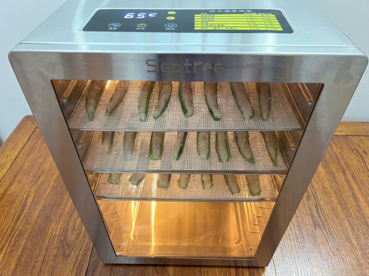 食品乾燥機にトレイをセットし、乾燥を開始する様子。