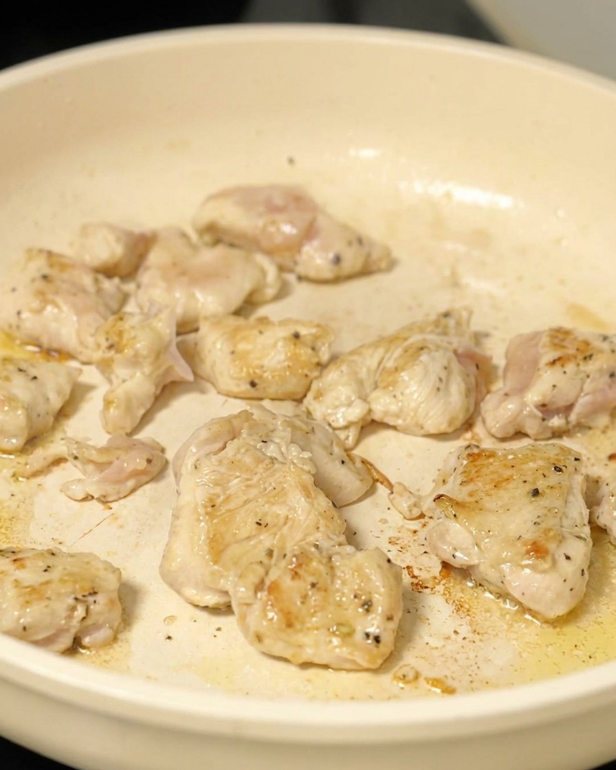 フライパンで一口大の鶏肉を、表面に焼き色がつくまで炒めている様子。