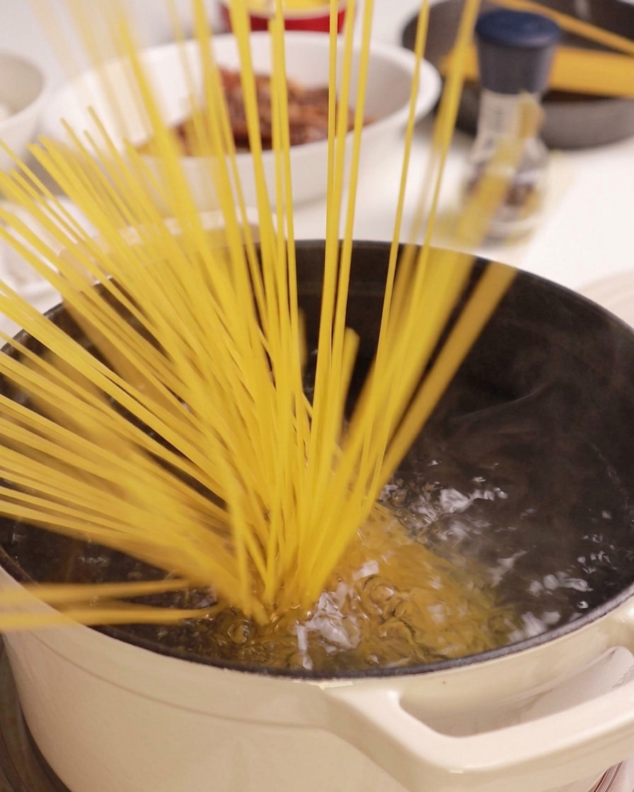 沸騰したお湯の中に乾燥したスパゲッティの束を入れている様子。