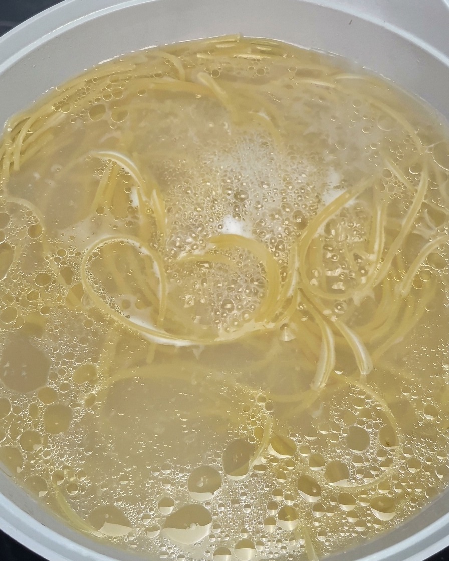 激しく沸騰するお湯の中で、スパゲッティが柔らかくなっていく様子。