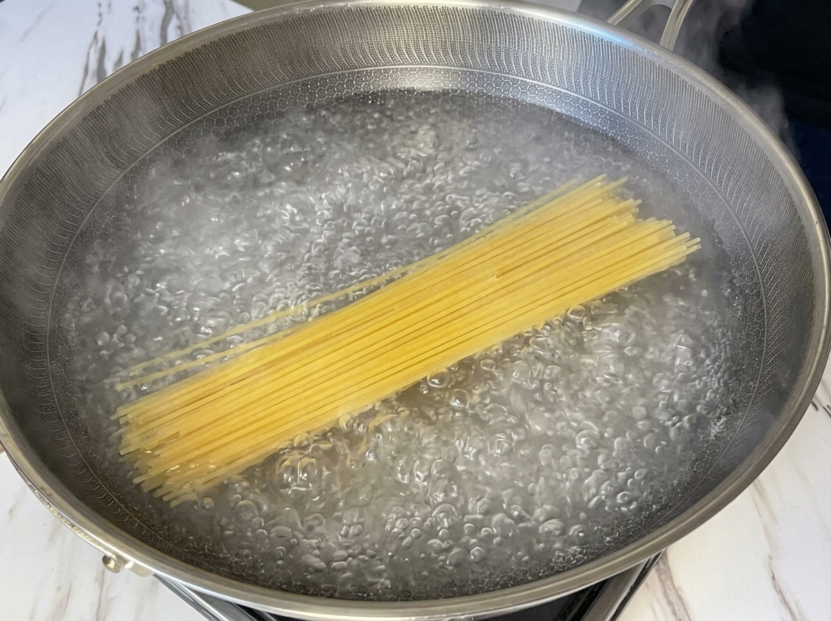 沸騰したお湯の中にスパゲッティを入れている様子。
