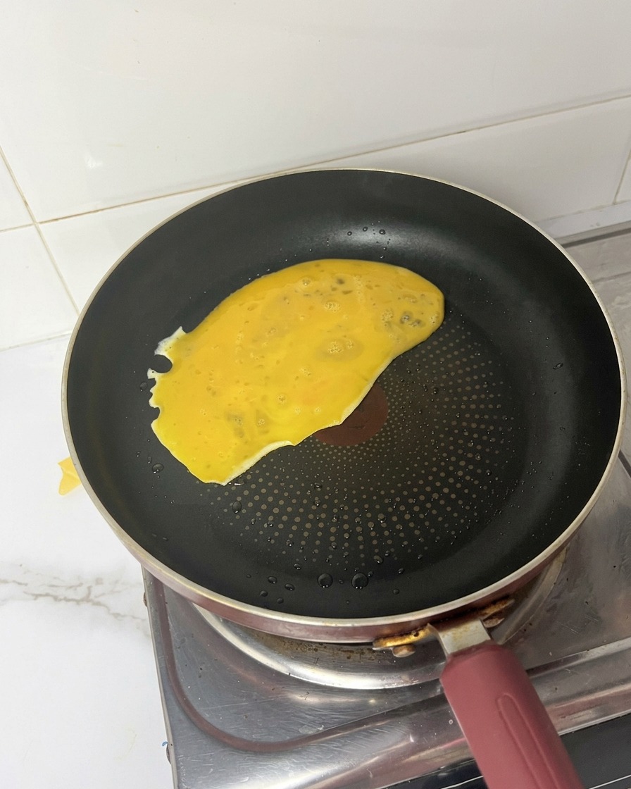熱したフライパンに黄色い卵液が広がっていく様子。