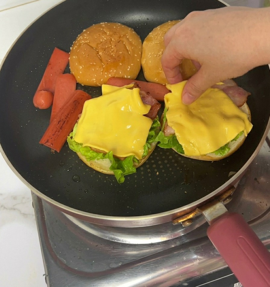 トングを使って、チーズの上に焼いたハムをのせる様子。
