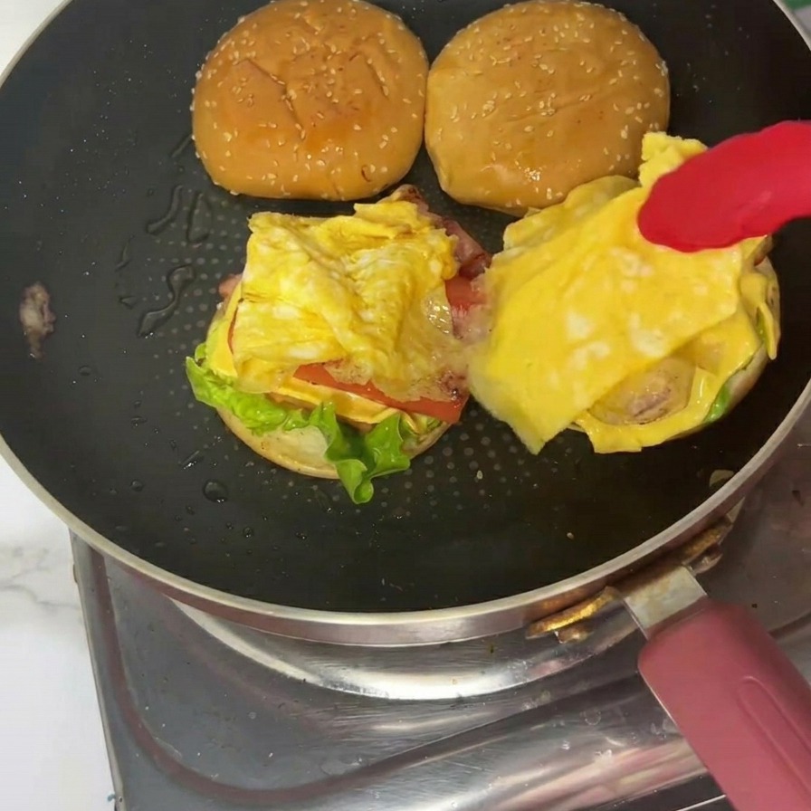 完成したバーガーに上のバンズをのせて仕上げる様子。