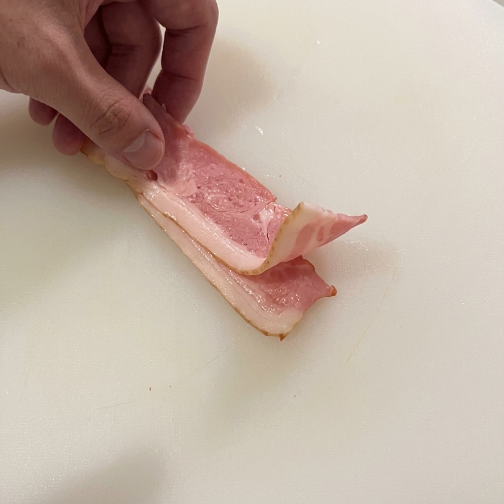 生のベーコンを一口大の細切りにしている様子。