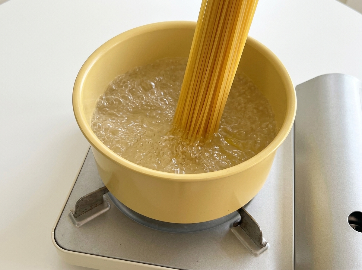 沸騰したお湯が入った鍋に、乾燥スパゲッティを入れる様子。