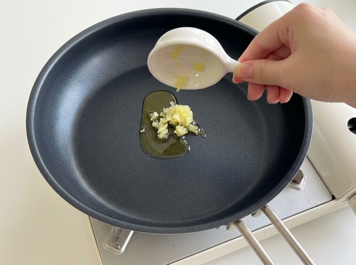 加熱したフライパンに、みじん切りにしたにんにくを入れる様子。