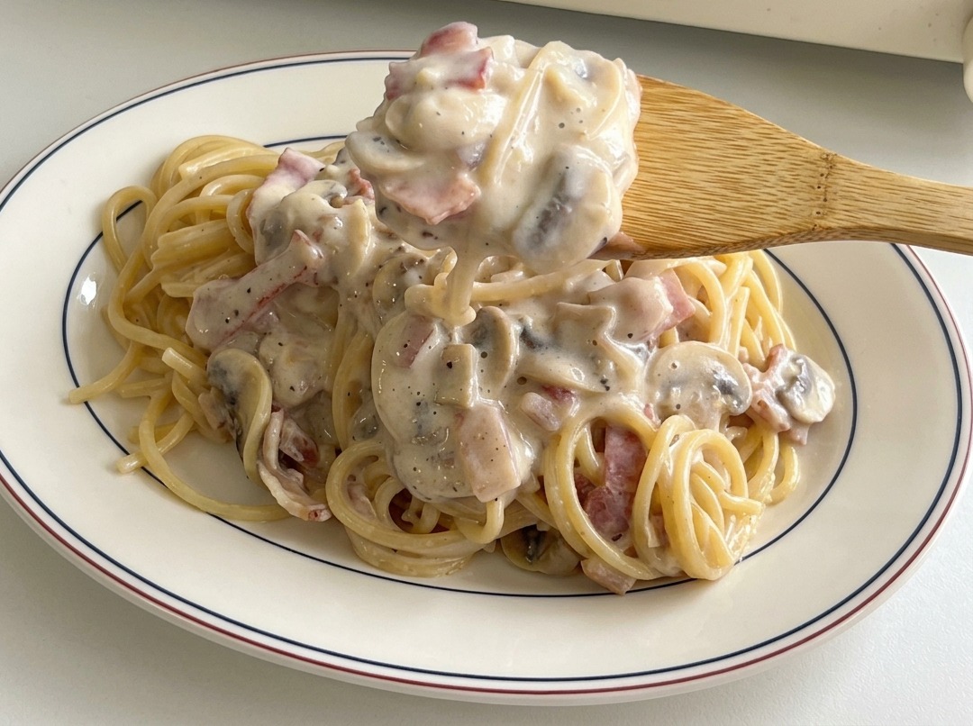 お皿に盛ったパスタの上から、具材たっぷりのソースをかける様子。