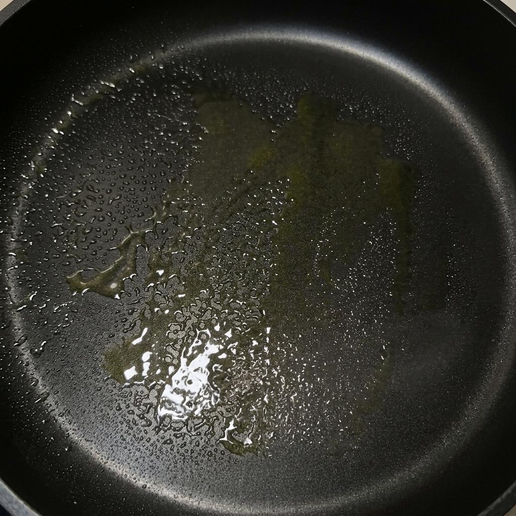 オリーブオイルと溶けたバターが広がる黒いフライパン。
