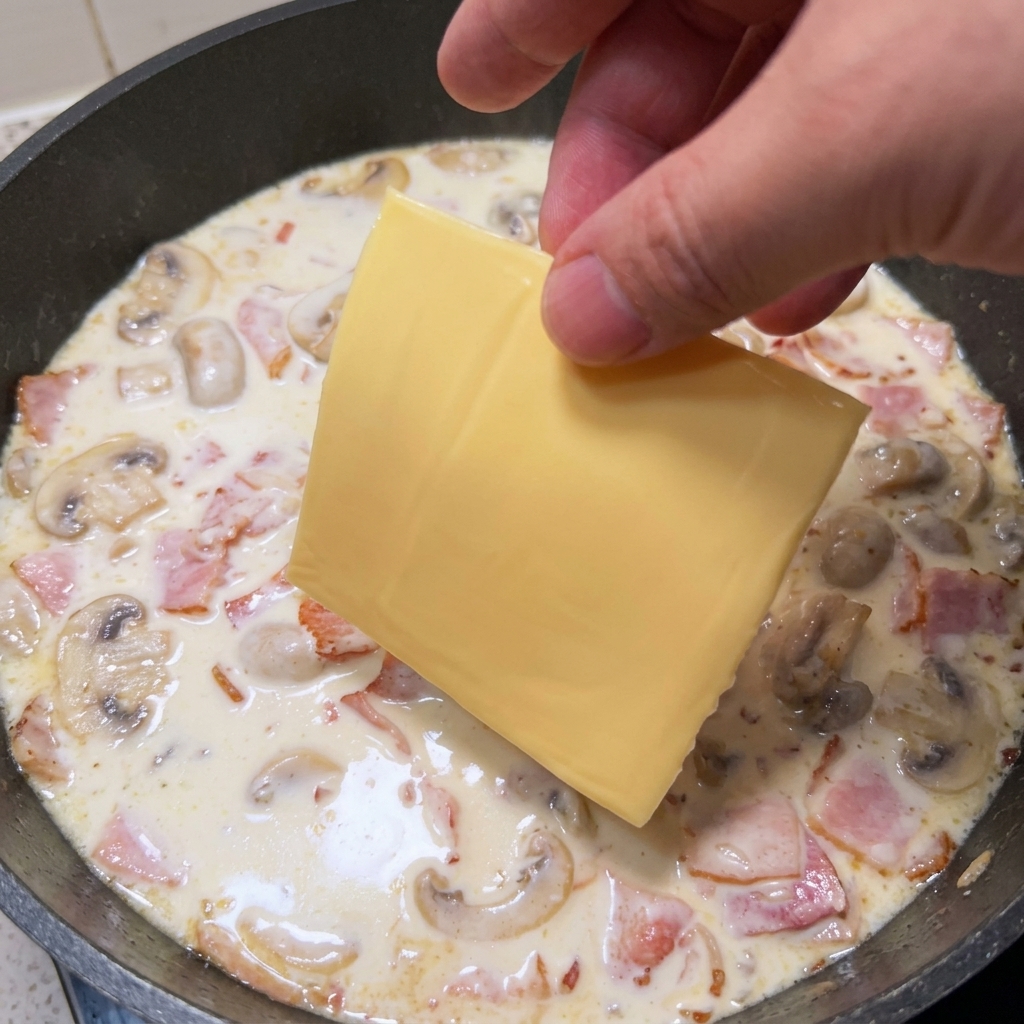 とろりとしたクリームソースの上にスライスチーズを乗せている様子。