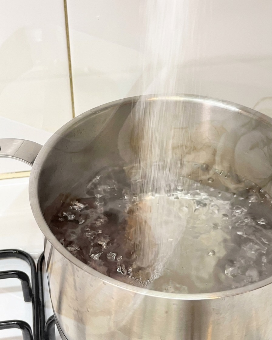 沸騰した鍋のお湯にたっぷりの塩を入れている様子。