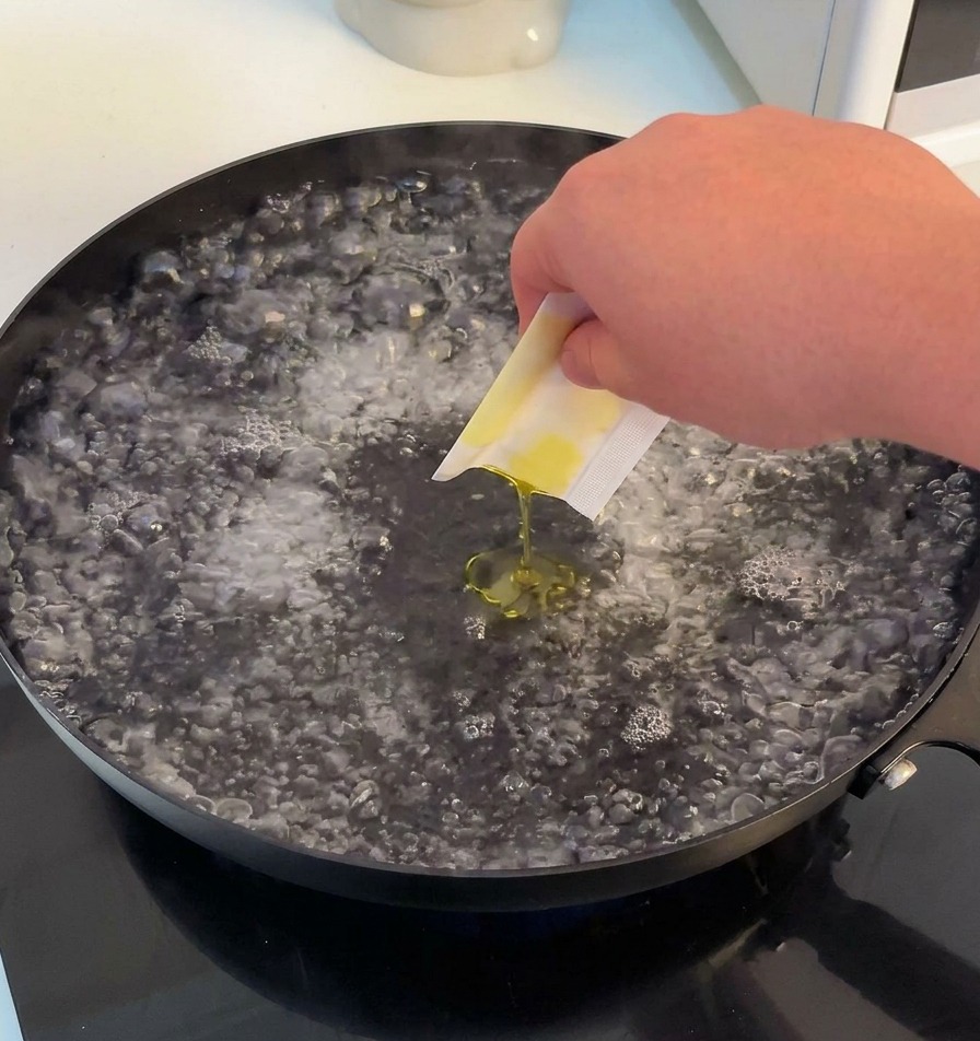 激しく沸騰したお湯が入った広い鍋に、塩とオリーブオイルを入れている様子。