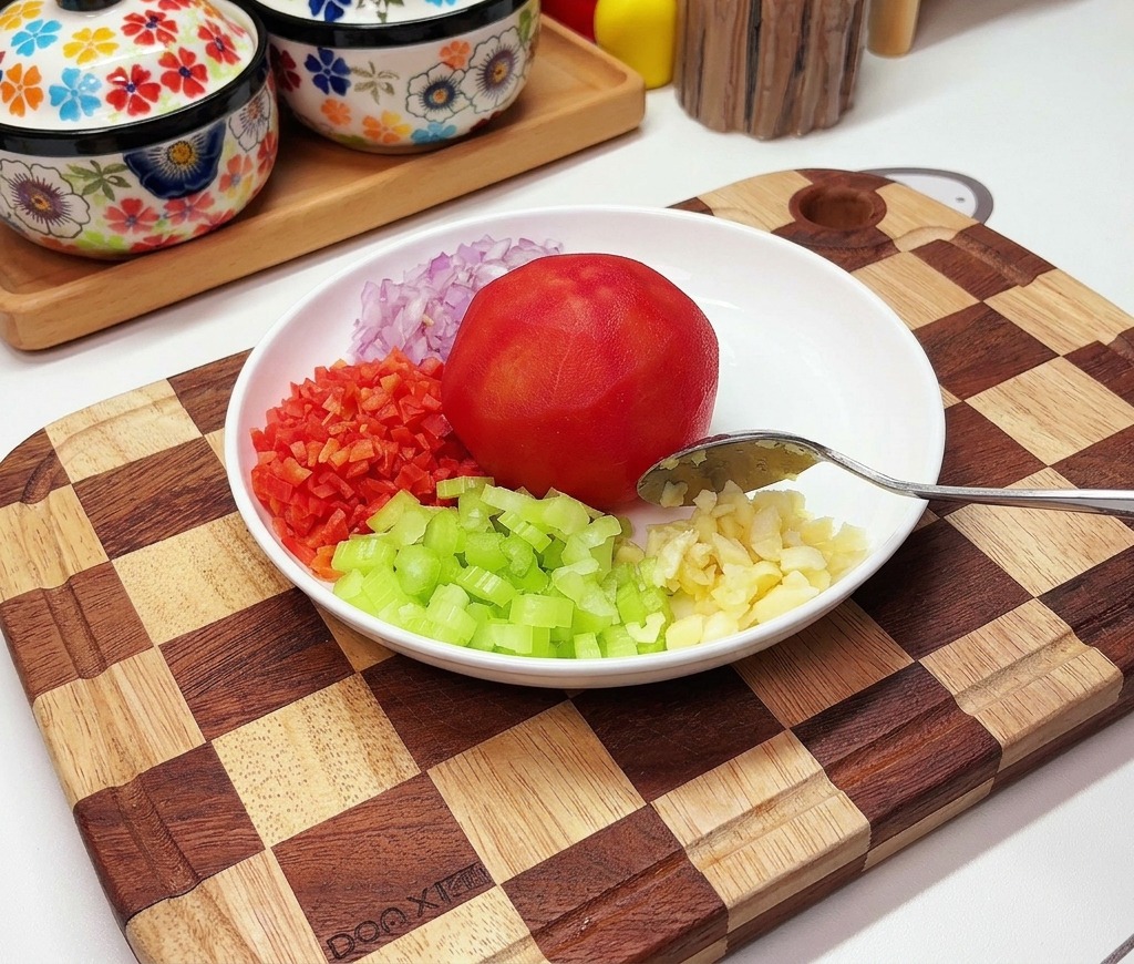 白い皿に湯むきした丸ごとのトマト、みじん切りにした赤玉ねぎ、にんじん、セロリ、おろしにんにくが並んでいる様子。