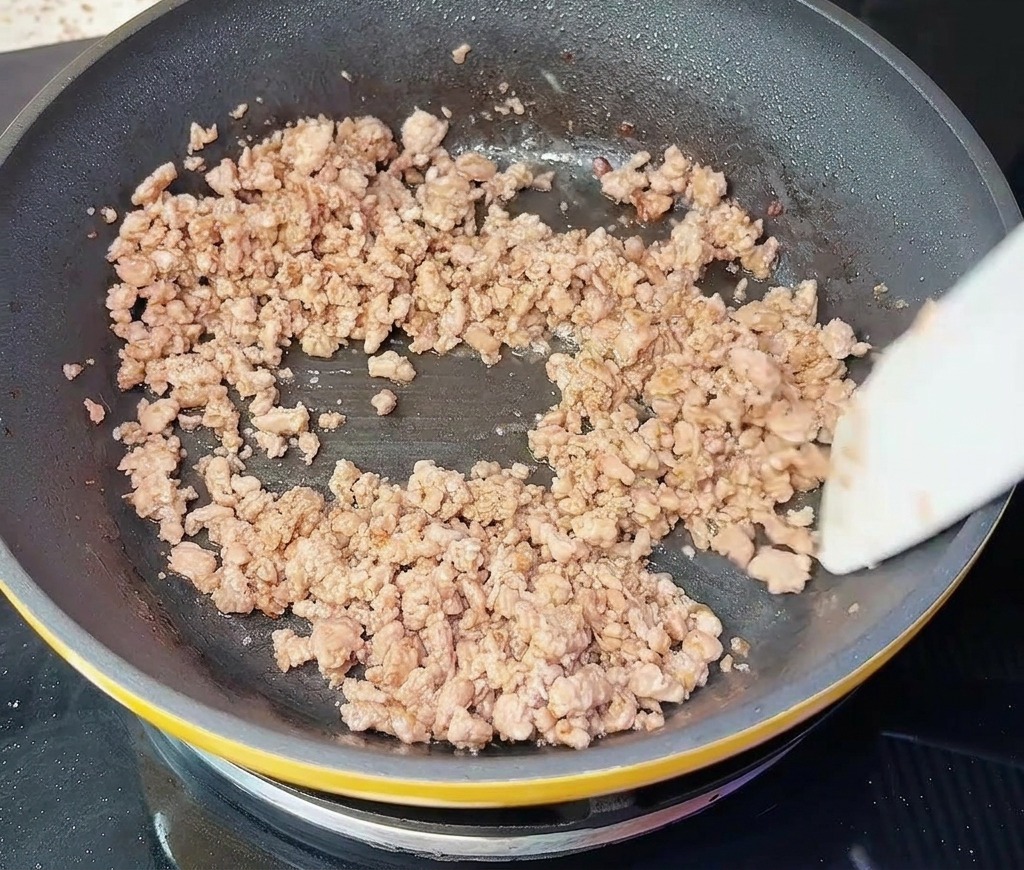 ヘラを使って、全体が茶色く色づき、パラパラになった挽き肉を炒めている様子。