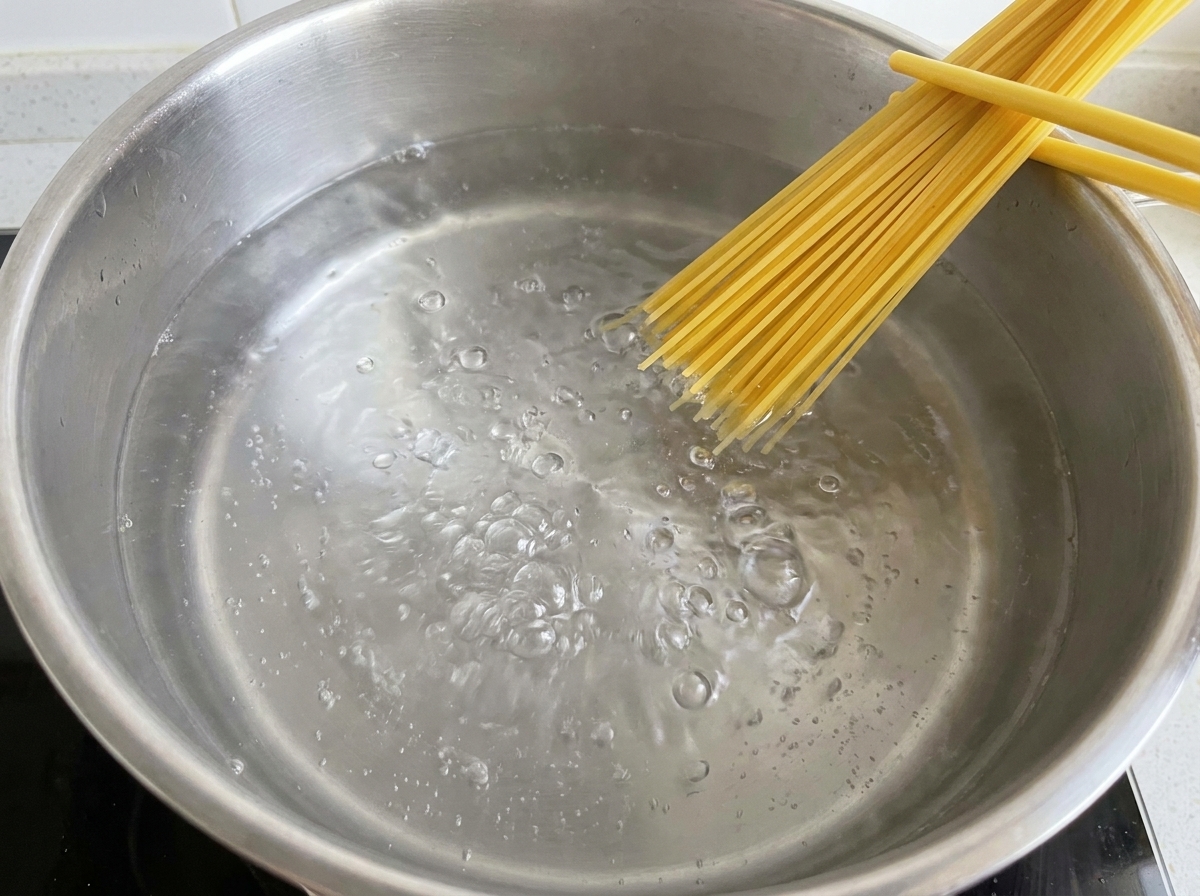 沸騰したお湯の中に乾燥スパゲッティを沈めている様子。