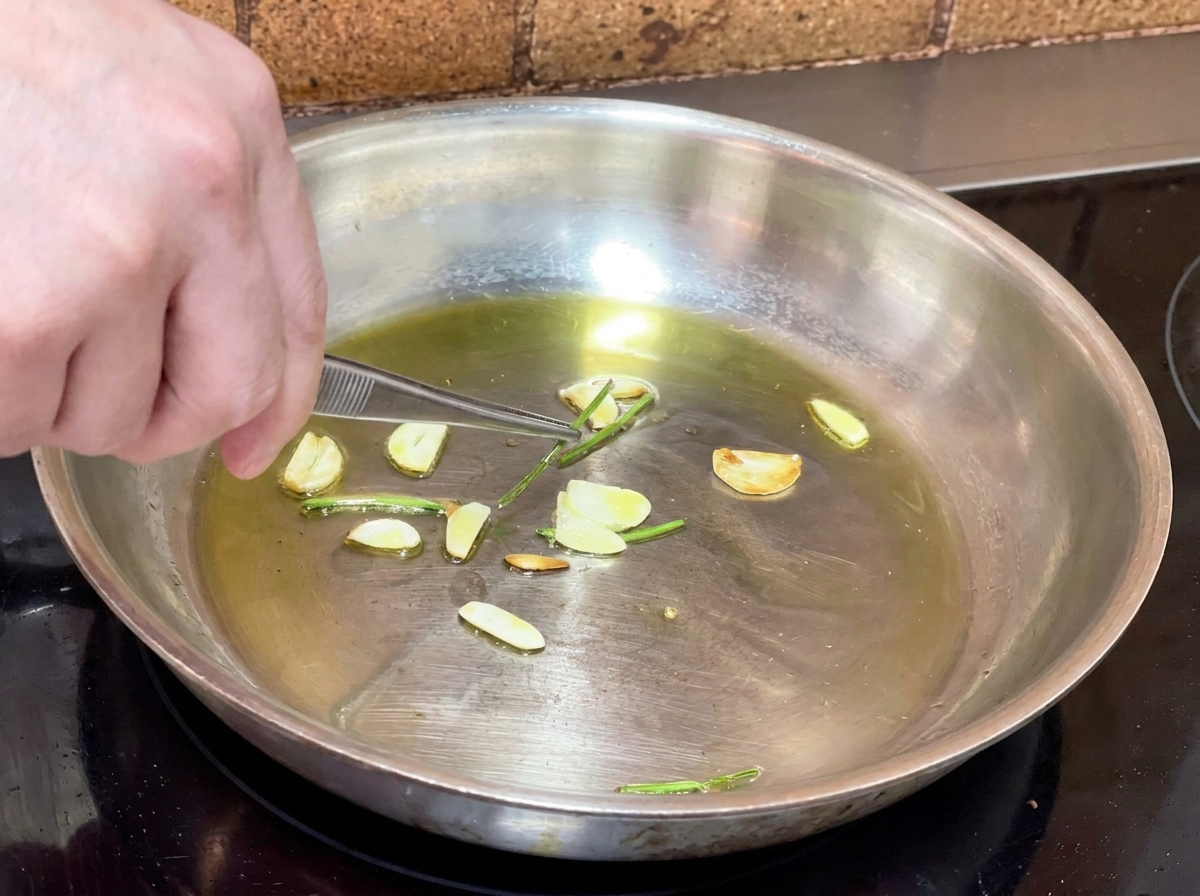 にんにくオイルの中から、ピンセットで炒めたパセリの茎を取り出している様子。