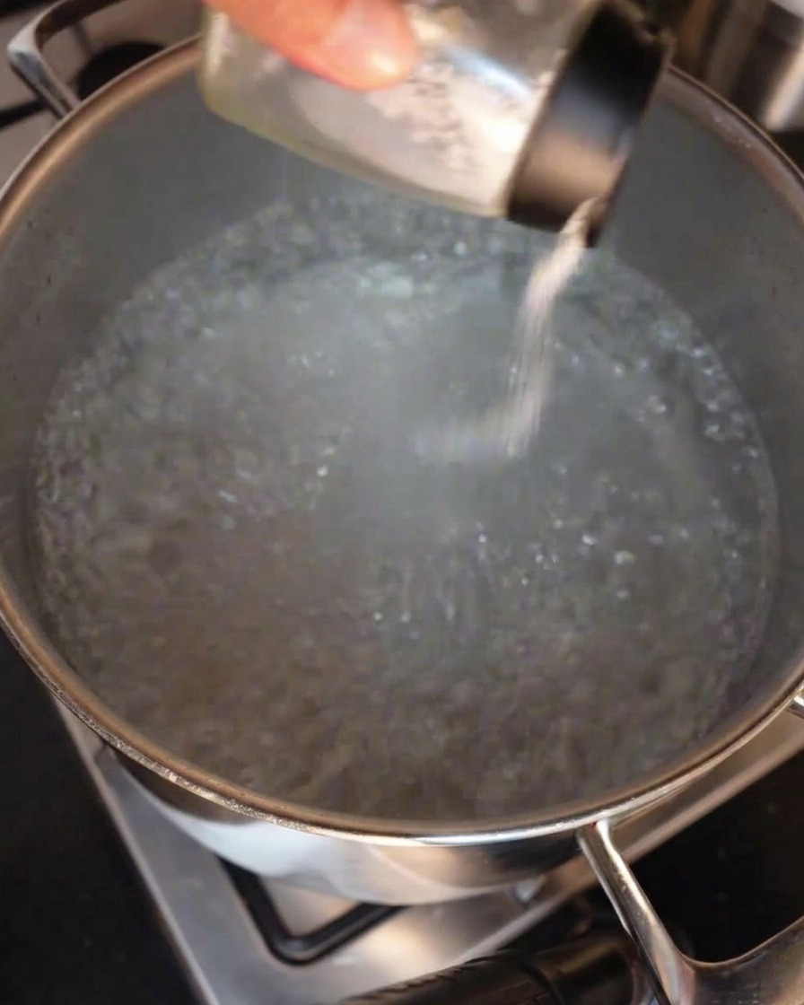 沸騰したたっぷりのお湯が入った鍋に、塩を振り入れている様子。