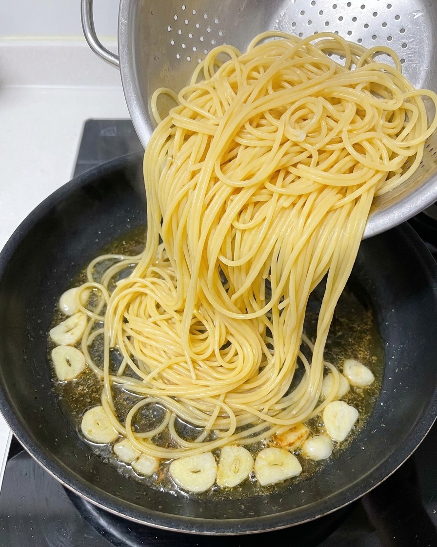 茹で上がったスパゲッティを、オイルの残ったフライパンに移している様子。